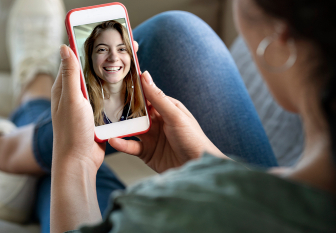 Uma menina segura o celular no qual assiste a um vídeo